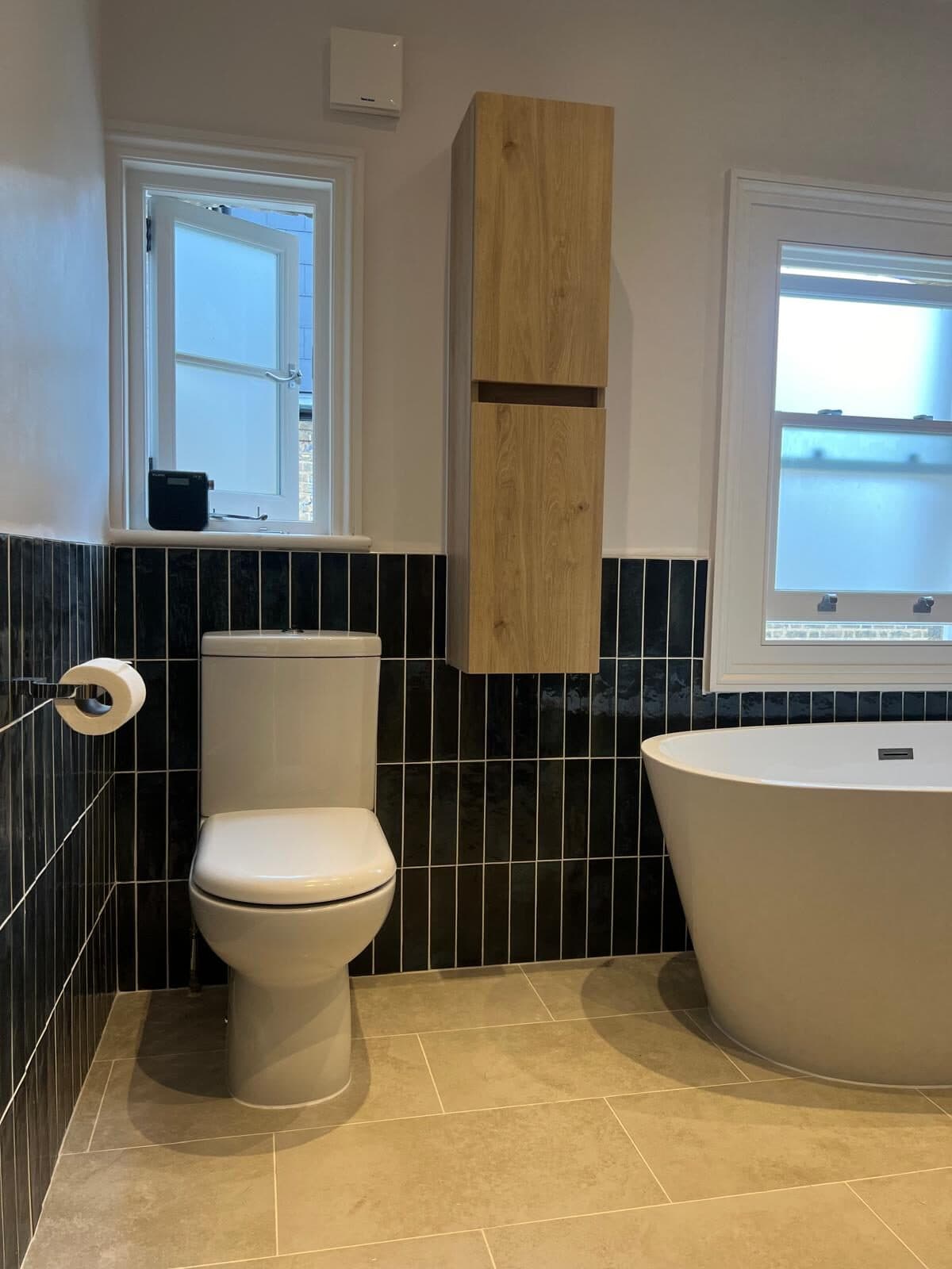 Freestanding bath against deep green tiles